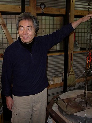 Hosokawa Morihiro in front of Raku Kiln showing flame height
